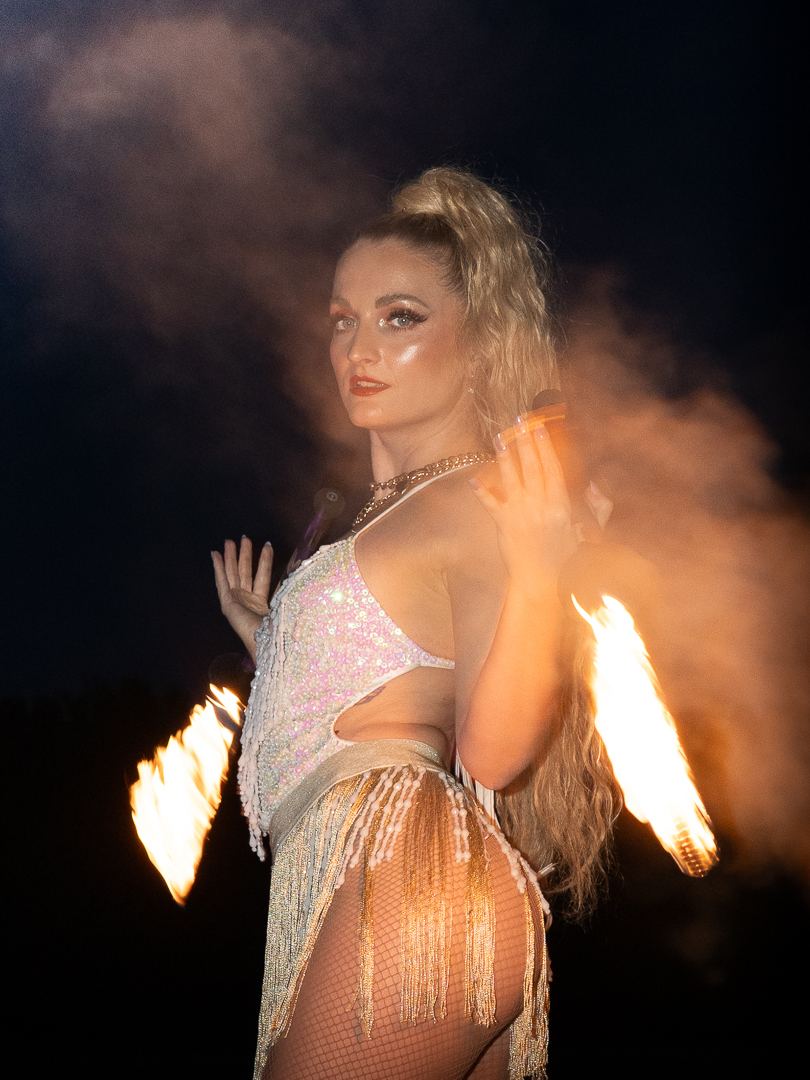 Fire performer spinning flaming fans in a smoky night performance at the Ibiza White Party, The Sanctuary